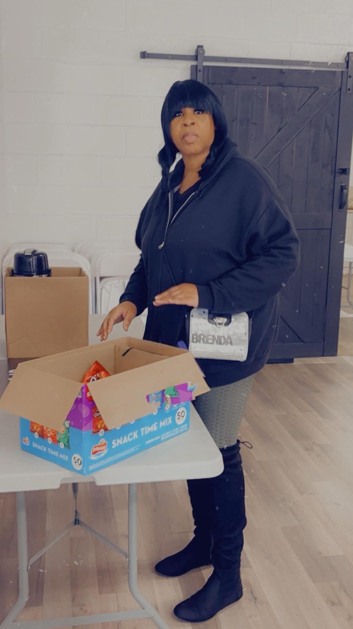 Volunteer Brenda stands with snack boxes for a community event