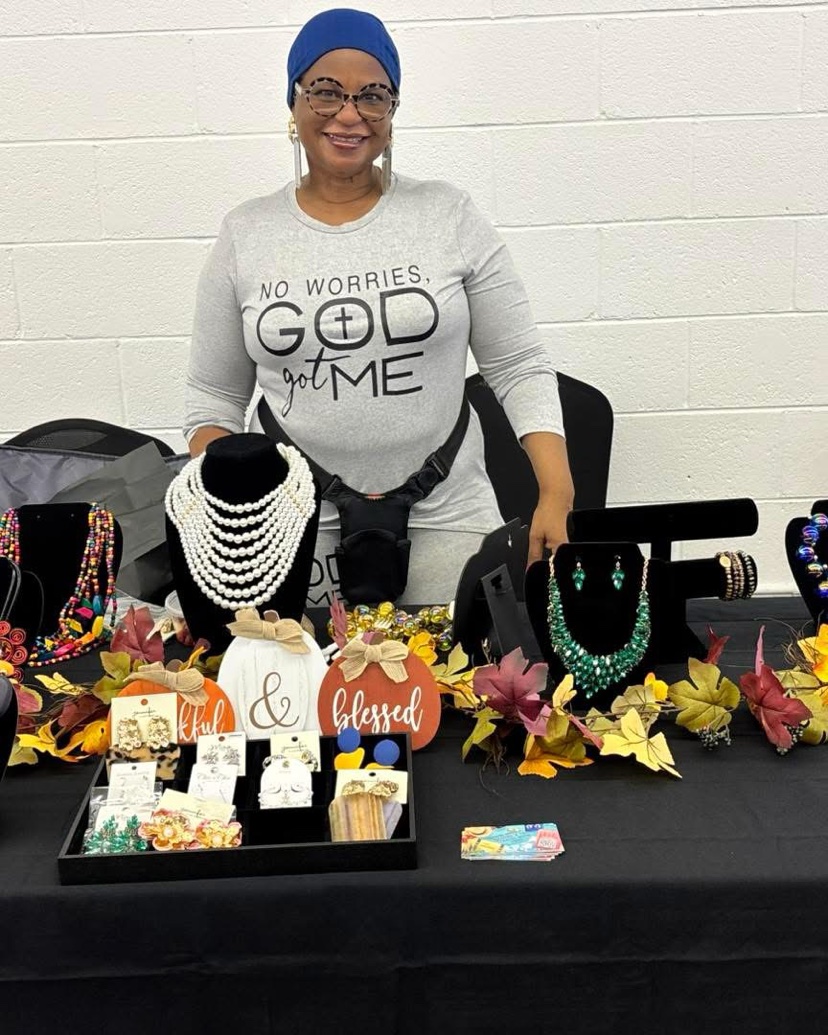 A local entrepreneur stands behind her vendor table of handmade jewelry, necklaces and earrings