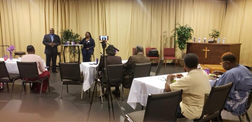 Speakers address families seated at tables during a Family Life Planning gathering
