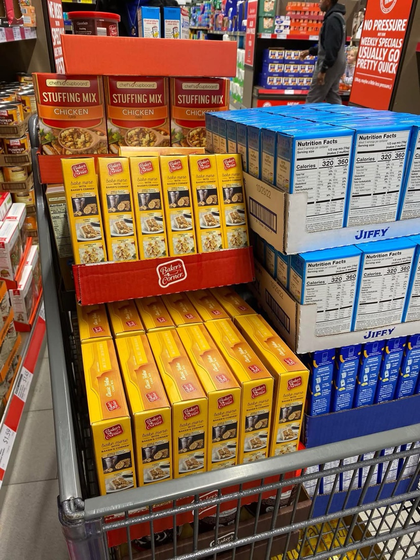 A shopping cart loaded with stuffing mix, cake mix and cornbread mix for holiday food boxes