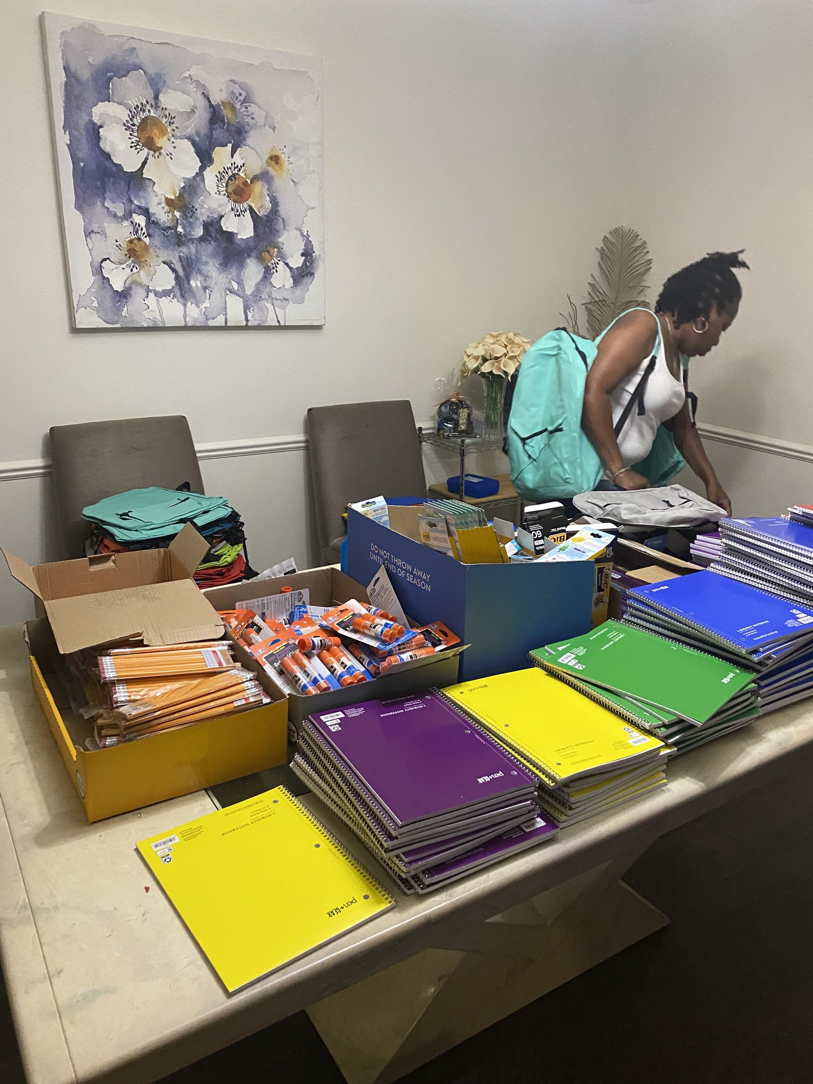 A volunteer packing backpacks with notebooks and supplies