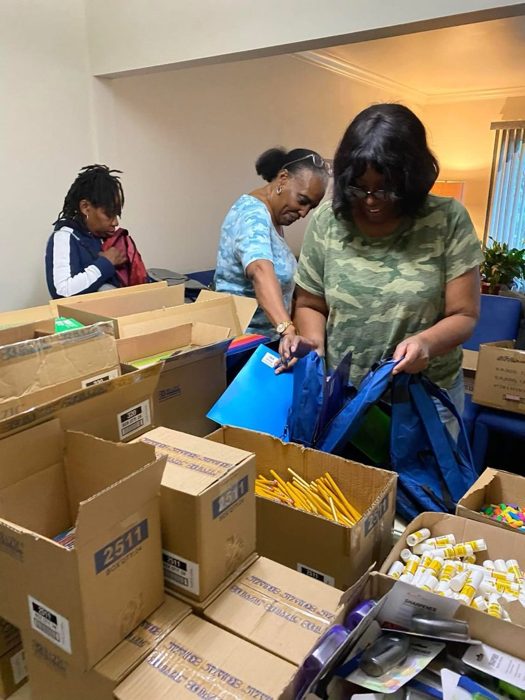 Volunteers packing backpacks with school supplies.