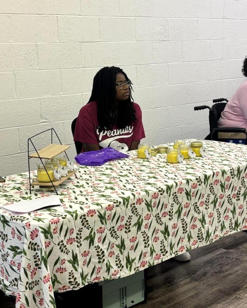 A young woman selling handmade candles at a vendor table