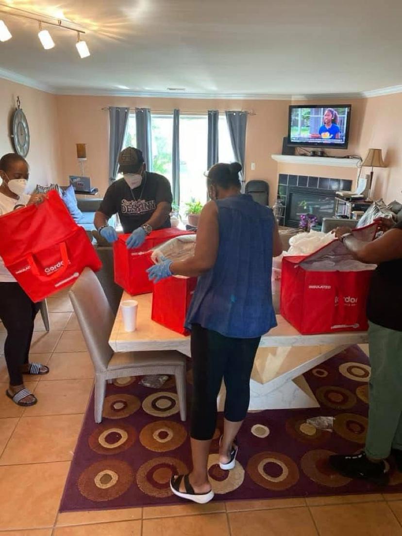 Volunteers packing red insulated meal bags at a table indoors