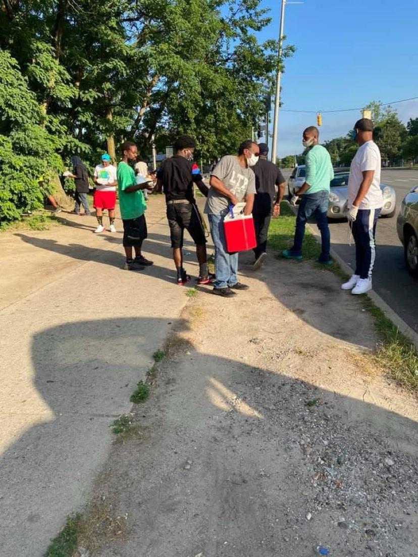 A group of men gathered on a sidewalk with a cooler during outreach